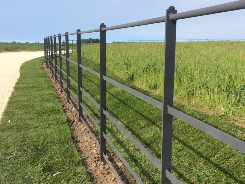 Estate railing along a grass bank with meadow beyond