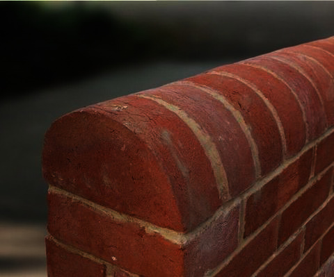 Half-round brick wall coping detail beside gravel edging