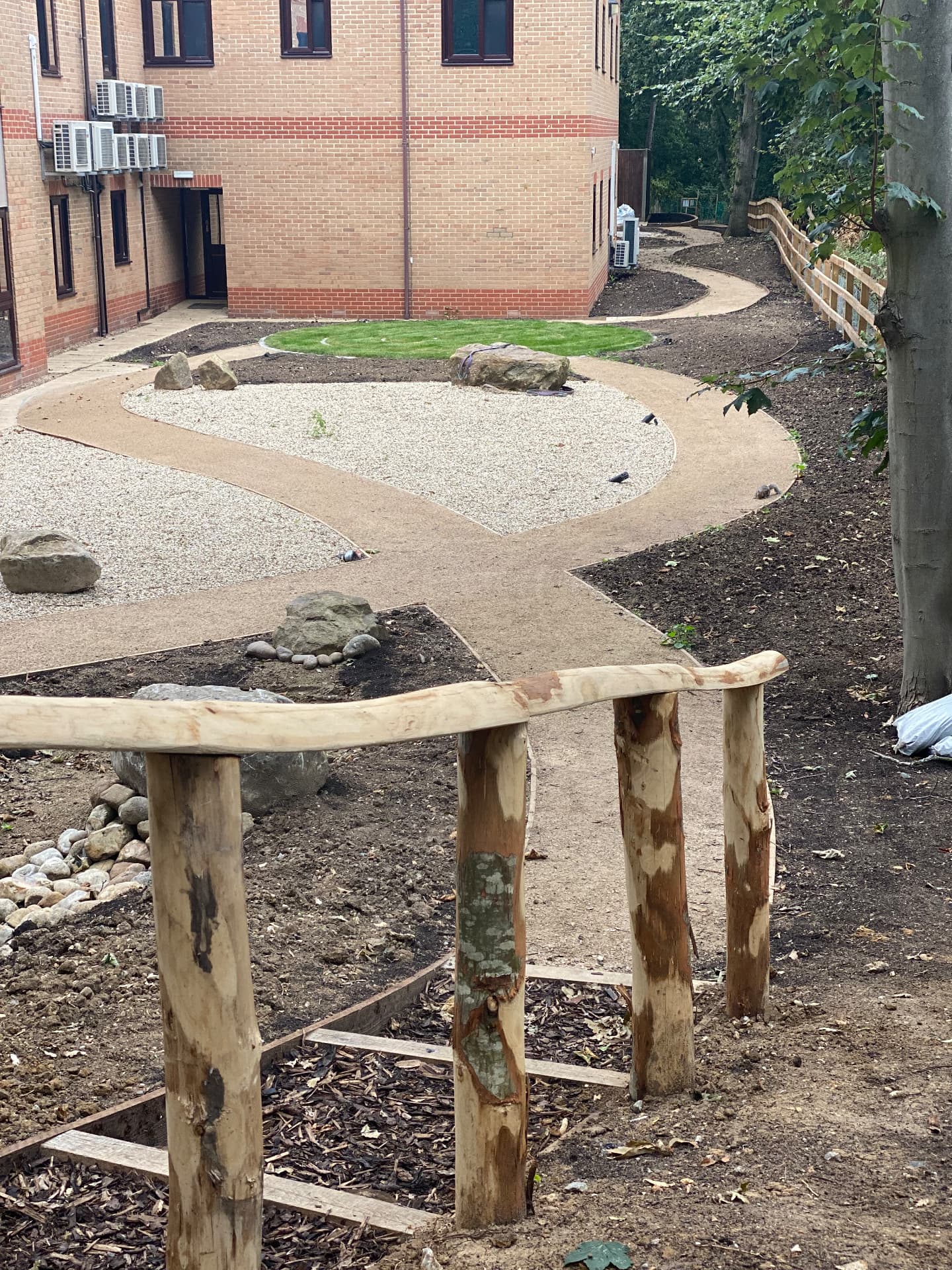 Partially constructed therapeutic garden with curved paths, gravel, boulders and timber railings