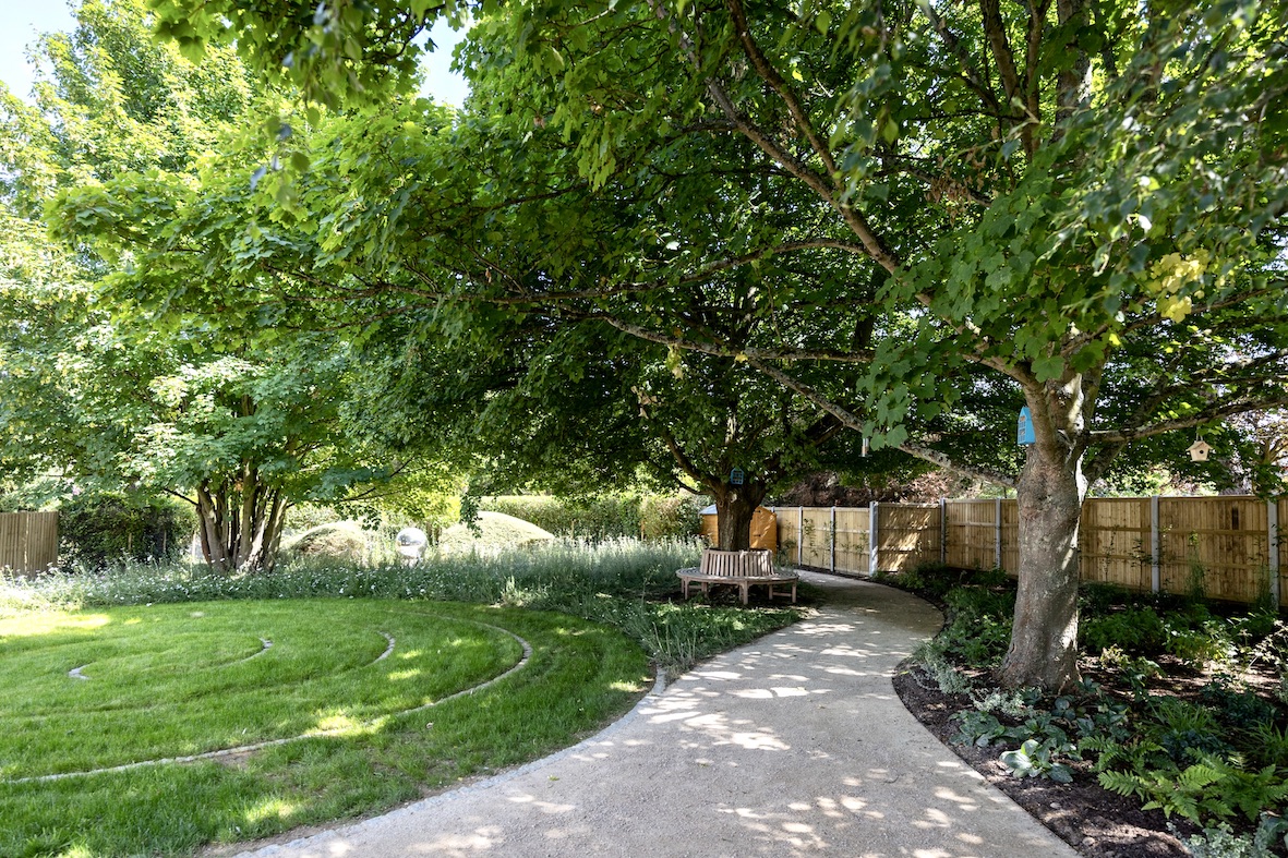 Curving garden path beneath mature trees at Forest Lane