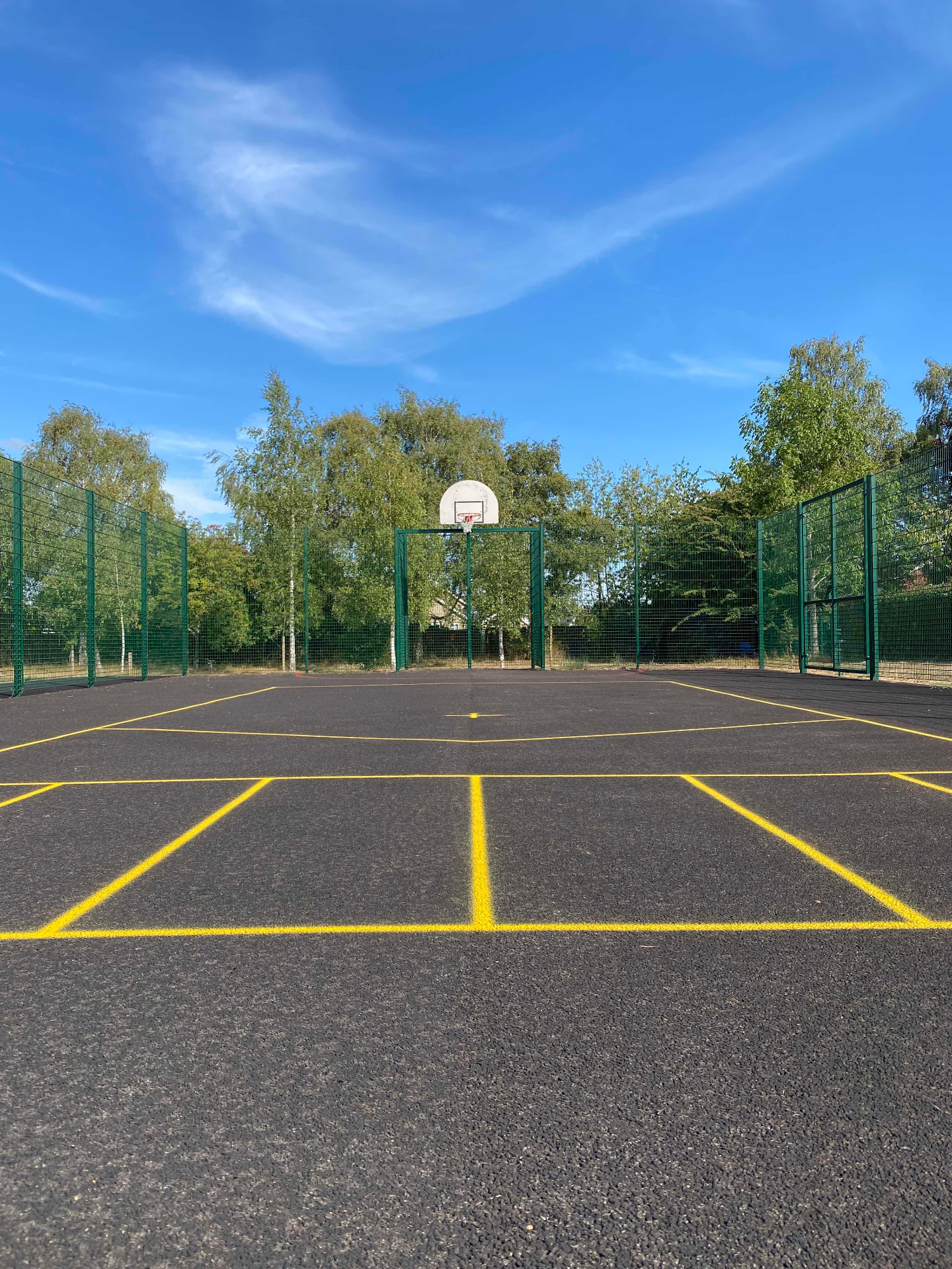 New multi-use games area framed by trees beneath a wide Suffolk sky