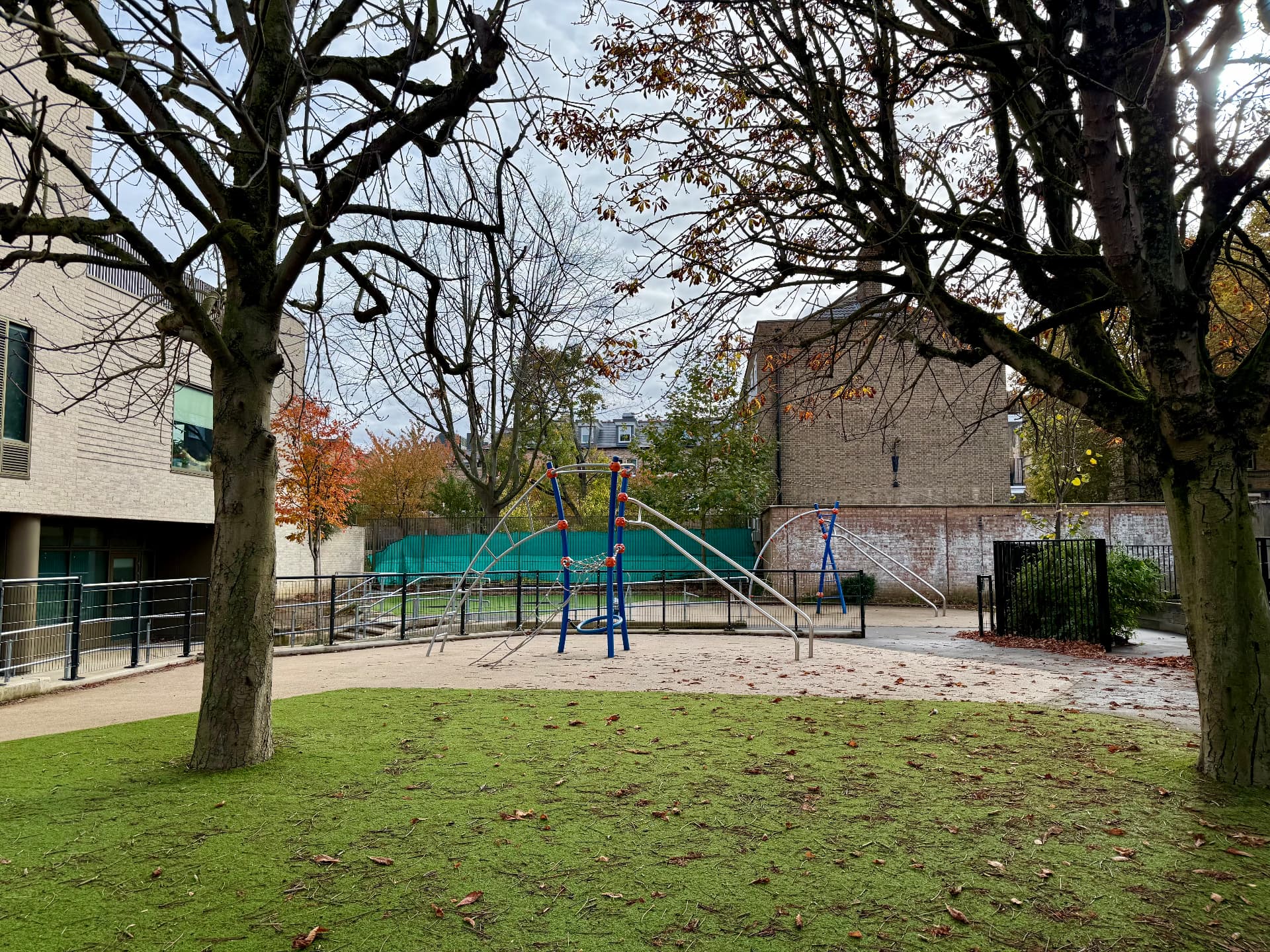 School playground with climbing equipment beneath mature trees