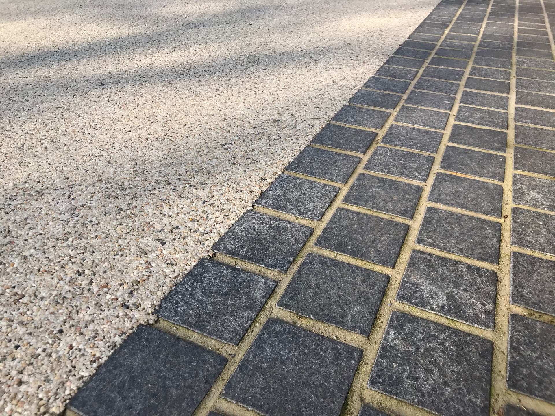 Detail of pale aggregate meeting dark linear paving