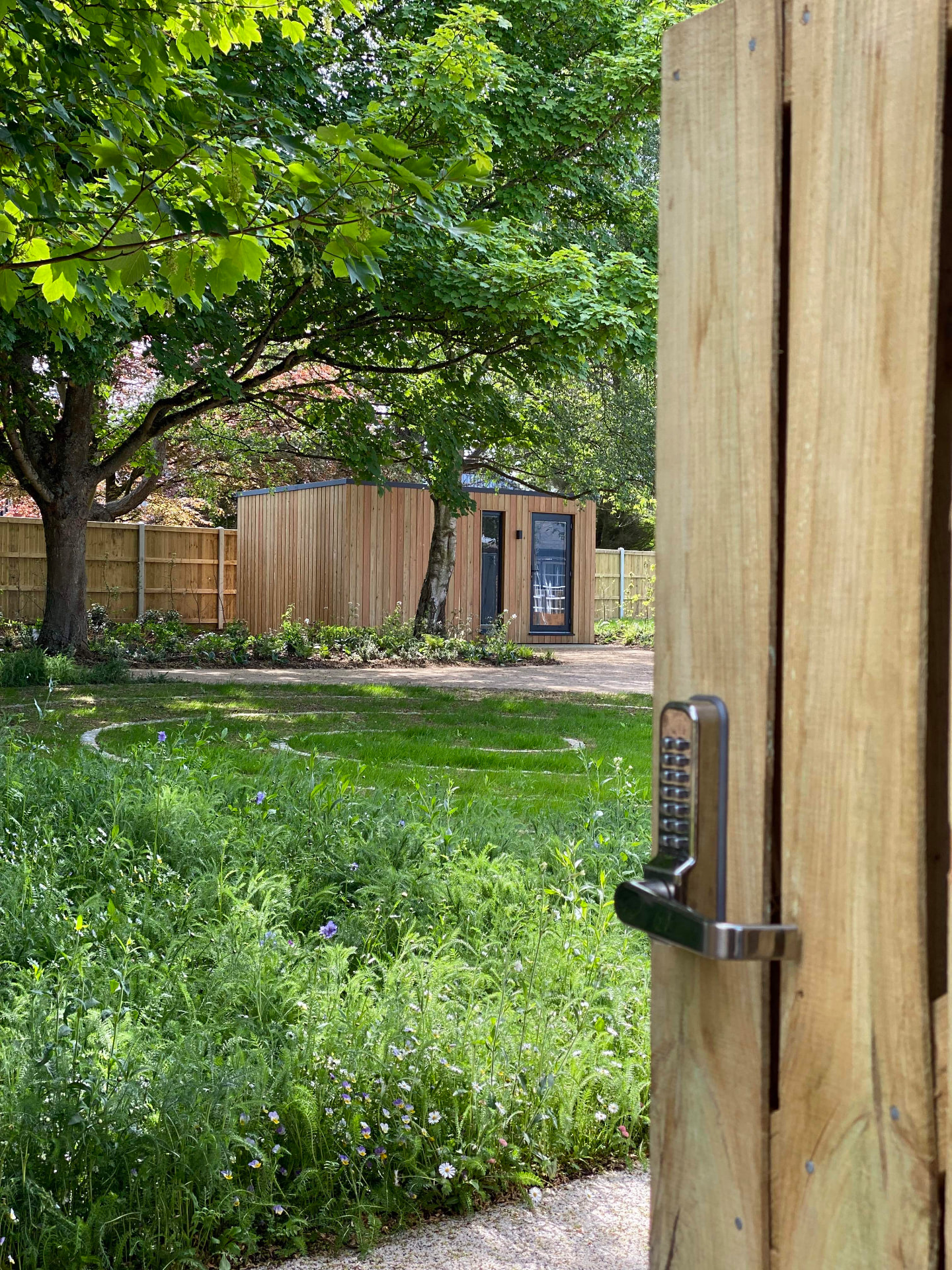 View through the open timber gate into the garden, with the therapy room beyond the wildflower planting