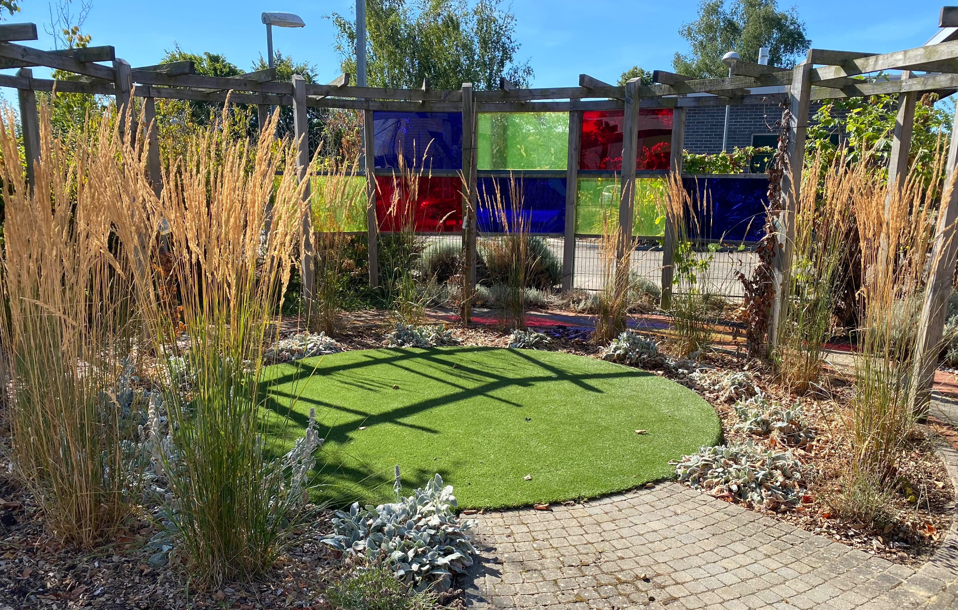 Sensory garden with layered planting, coloured panels and a circular lawn