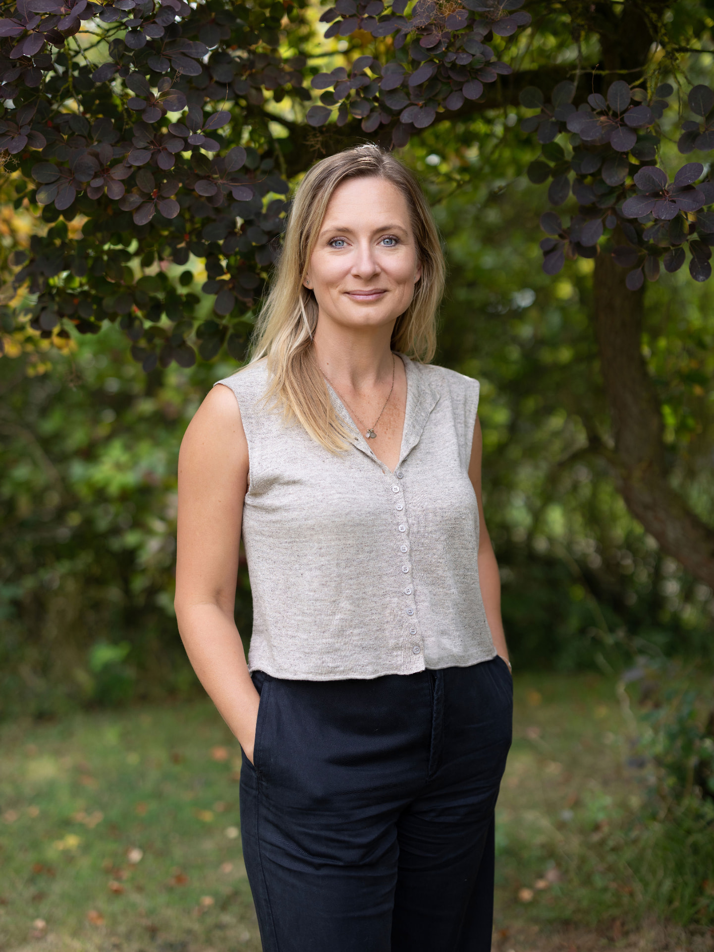Mia Niklasson standing beneath dark foliage in a woodland garden