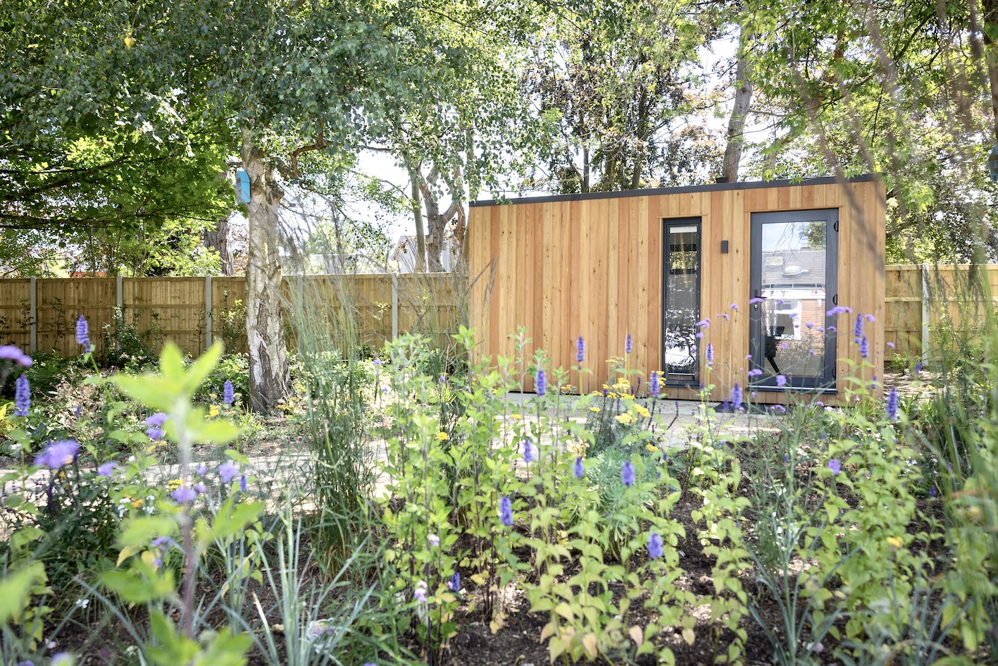 Timber-clad therapy room set within rich perennial planting and mature trees
