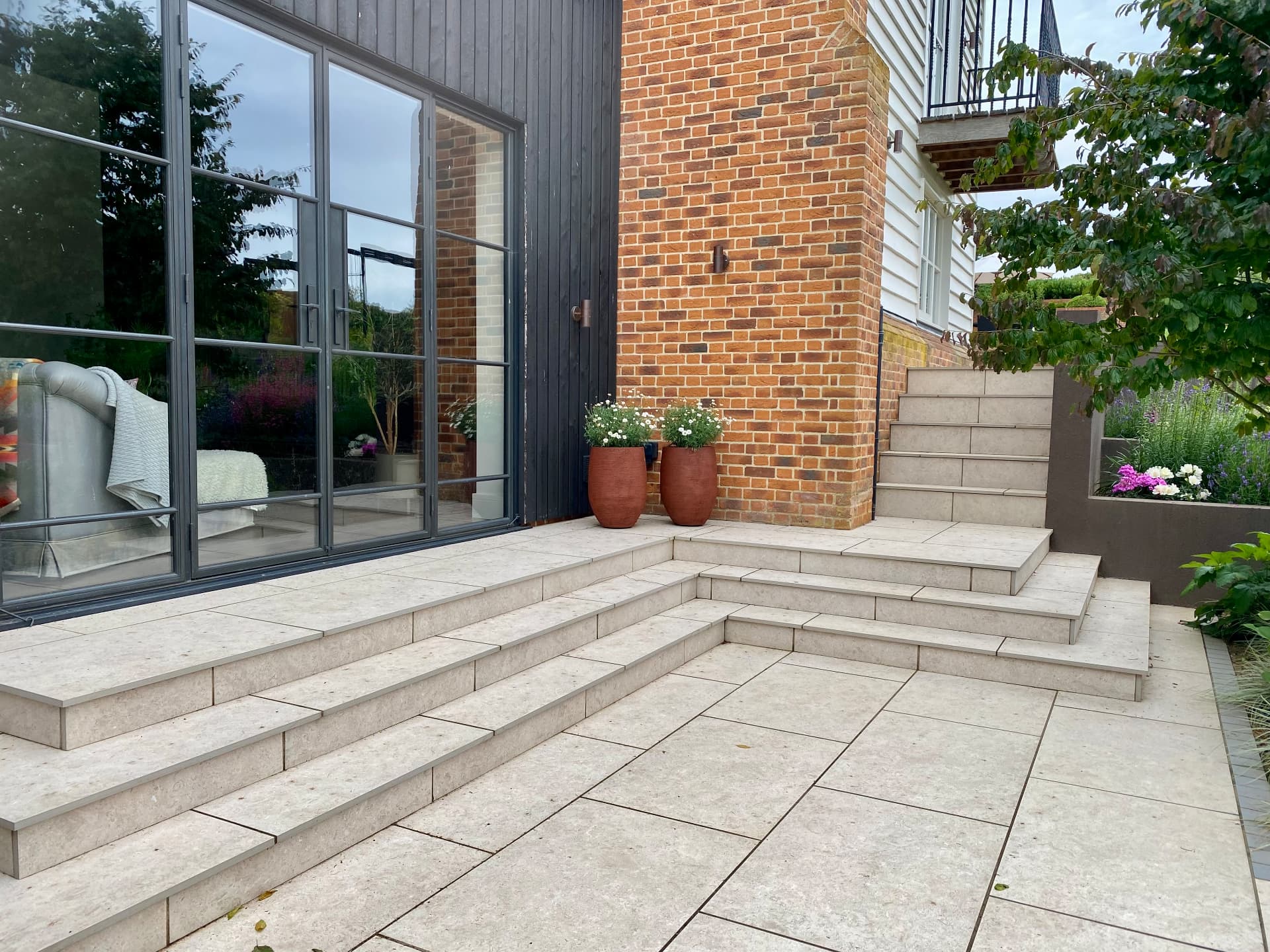 Steps and stone terrace beside the house glazing and brick chimney