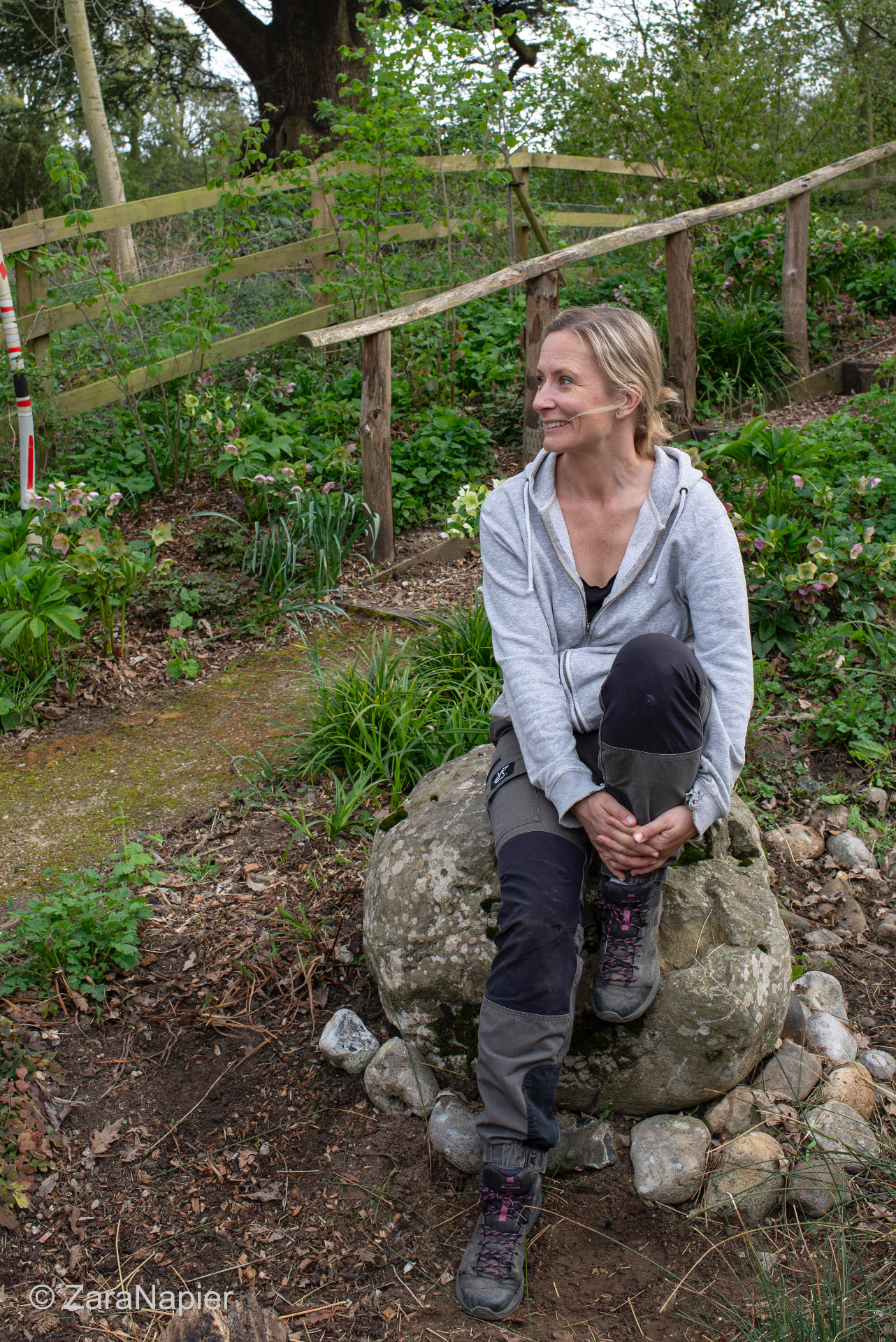 Mia Niklasson sitting on a boulder in a planted garden