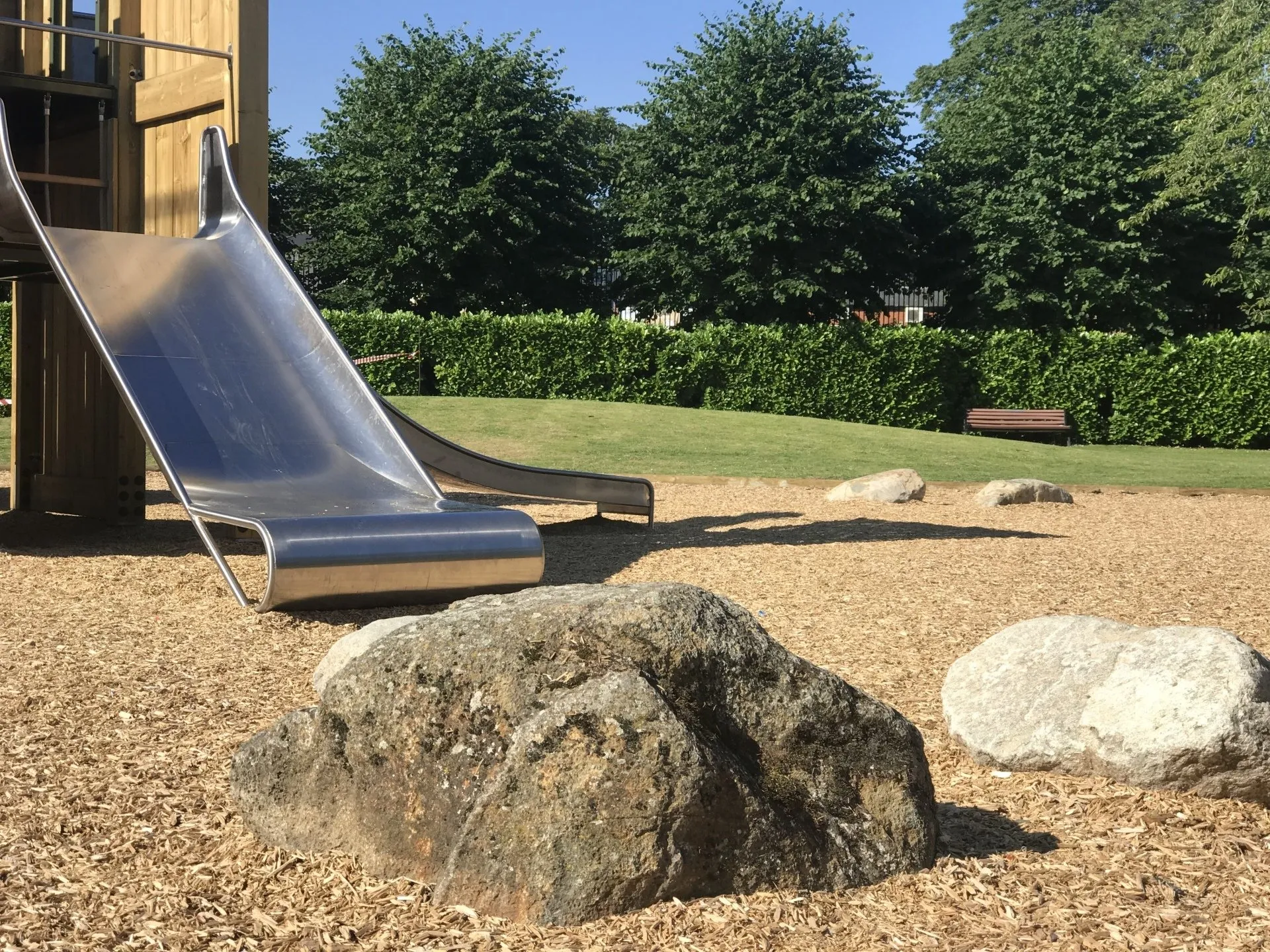 Stainless steel slide, natural boulders and grass within the completed playground