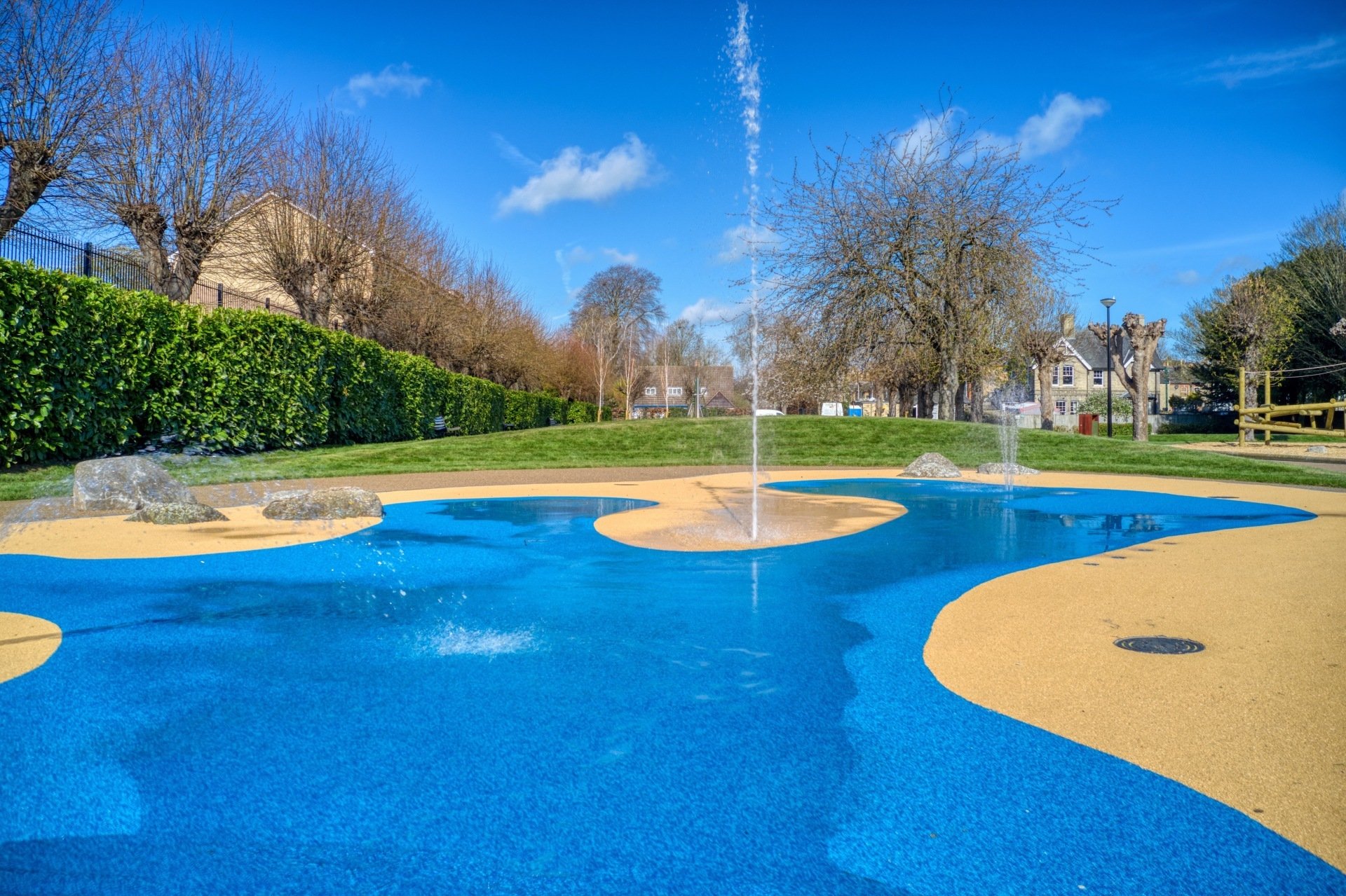 Blue and ochre accessible water-play surface with fountains in Newmarket Memorial Gardens
