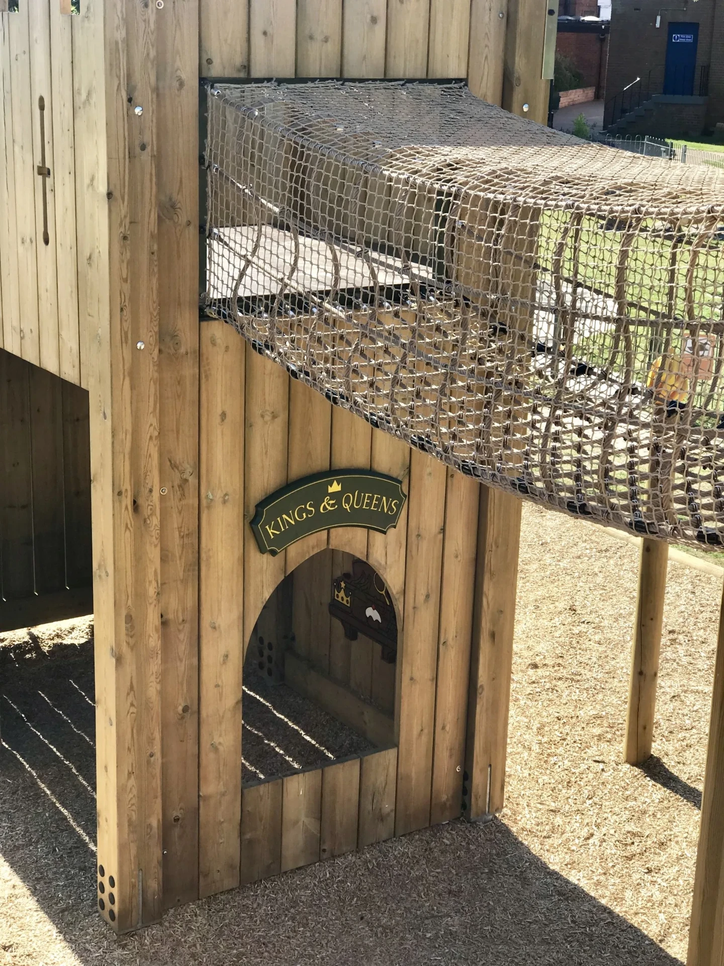Timber castle play structure with a suspended rope-net bridge